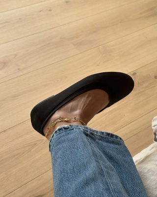 woman wearing black satin ballet flats and jeans