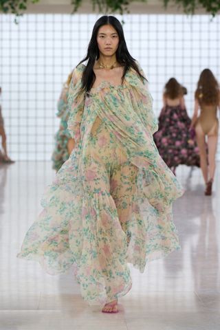 A woman at Chloe spring/summer 2025 show wearing a floral dress and pink sandals.