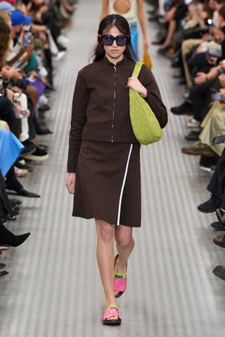 A woman wears pink slide with a brown two-piece set at miu miu spring/summer 2025 show.