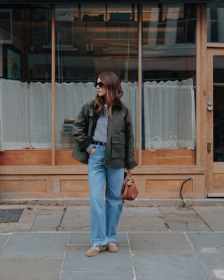 Woman wears barn jacket, blue jeans and trainers