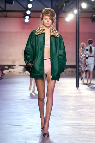 Woman in emerald green jacket on the runway