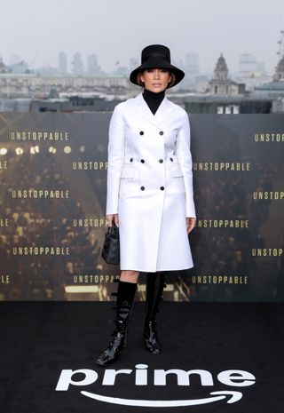 Jennifer Lopez wearing white trench coat and black calf high boots