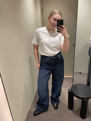 Woman wears white t-shirt, blue jeans and black loafers