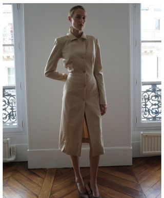 Elly McGaw wearing a tan button-down shirt dress with brown satin heels.