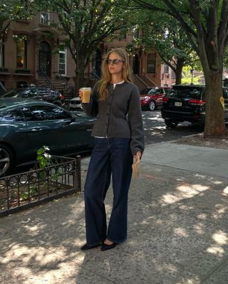 Woman wears waisted cardigan, blue jeans and black bag