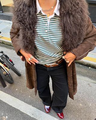 woman wearing cuffed denim outfit with striped polo shirt and brown coat