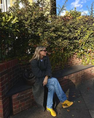 @lucywilliams02 wearing yellow trainers, jeans and long coat