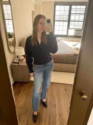 Nikki wears a navy cardigan, jeans, and black pumps.