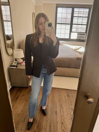 Nikki wears a gray blazer, black tank, and blue jeans.