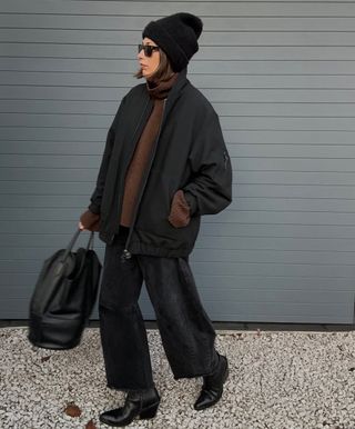 French woman wearing Western boots with baggy all-black outfit.