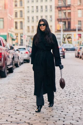 Neada Deters in New York wearing an all-black anti-trend outfit styled with a wool coat, a turtleneck, straight-leg trousers, and square-toe boots.