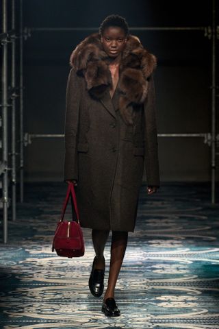 a Prada model wearing a fur-collar coat on the fall/winter 2025 runway during Milan Fashion Week