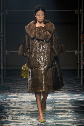 a Prada model wearing a fur-collar coat on the fall/winter 2025 runway during Milan Fashion Week