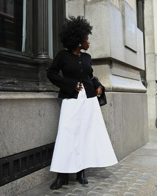 Danielle in a white A-line skirt and black cardigan