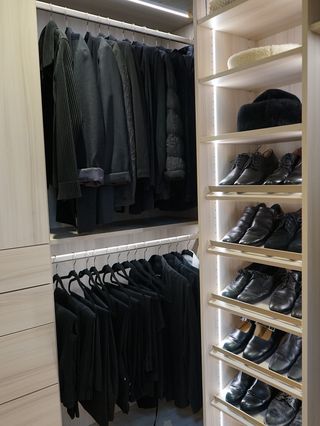 A photo of an organized closet with black clothes and black shoes.