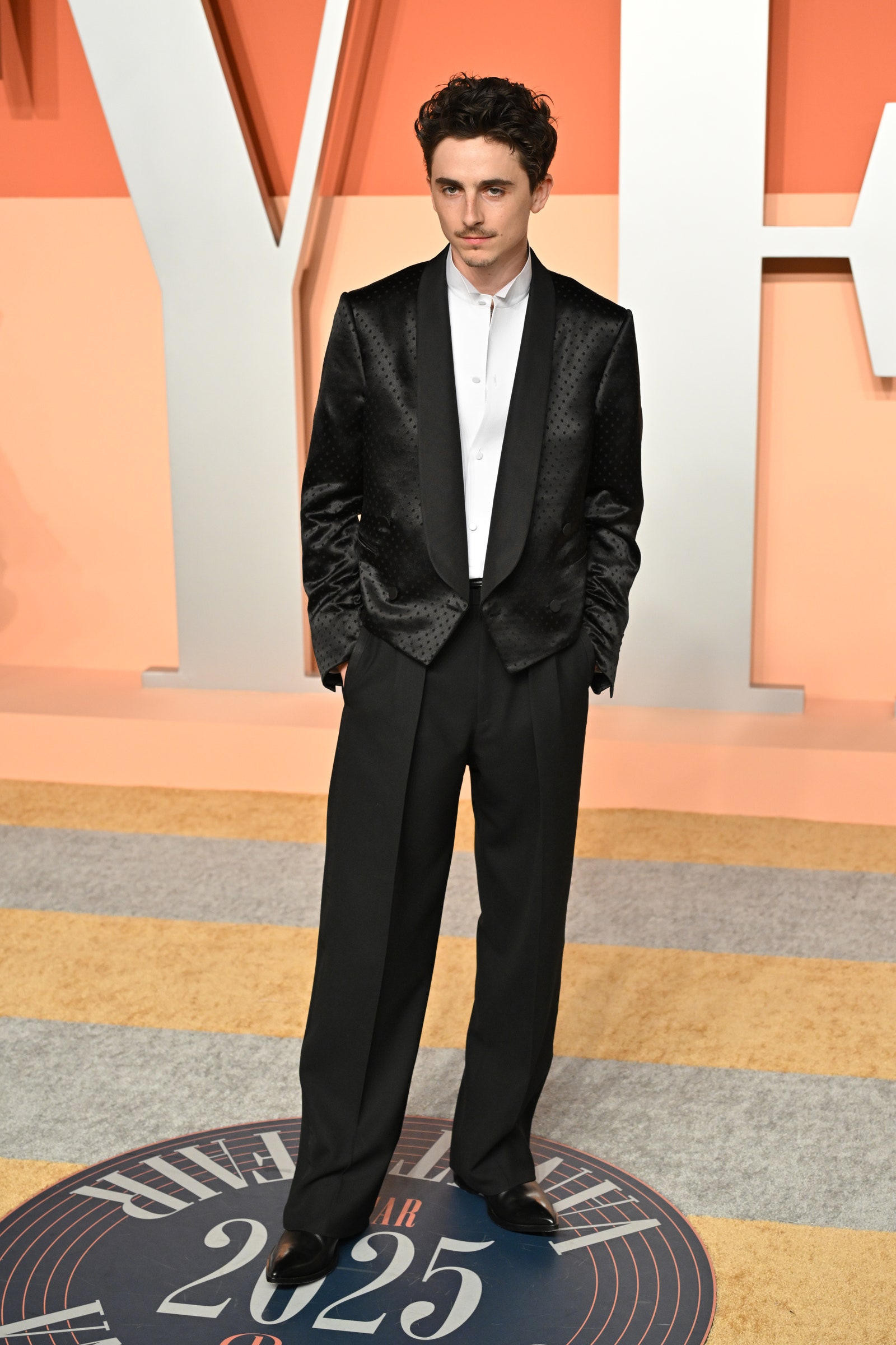 Image may contain Timothe Chalamet Clothing Formal Wear Suit Person Standing Tuxedo Adult Coat and Jacket