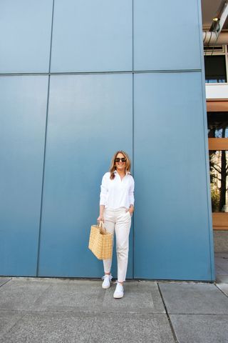 A Nordstrom stylist wearing a white button down, white jeans, and white sneakers.