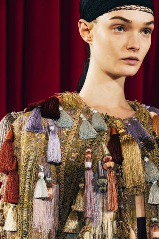 A close up of a model's shoulder with a fringe top on backstage at the Dries Van Noten F/W 25 show in Paris.