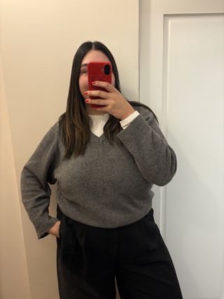 Editor Ana Escalante wearing gray v-neck sweater from Almina Concept in mirror selfie.