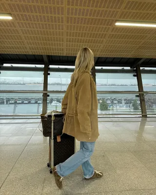 @josefinehj walking in an airport with suede coat, blue jeans, and suede sneakers