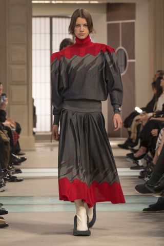 A model wearing a red-and-gray '80s-printed skirt and sweater set at the F/W 25 Louis Vuitton show.