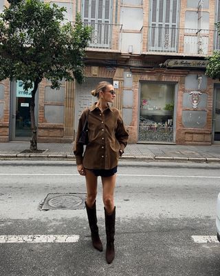 Woman wearing oversize button-down and miniskirt with tall suede boots.