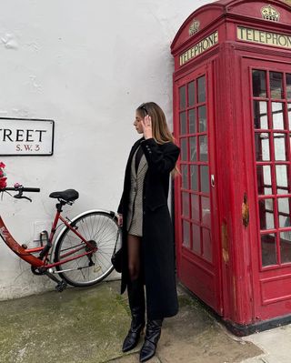 Woman wearing long black coat with tall black boots.