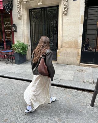 woman wearing white slip dress, leather jacket, and sneakers outfit