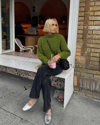 woman wearing green sweater and light black jeans