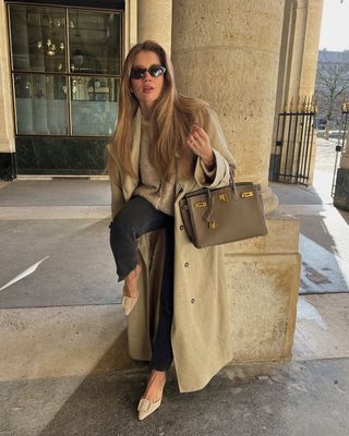 woman wearing camel long coat and light black jeans