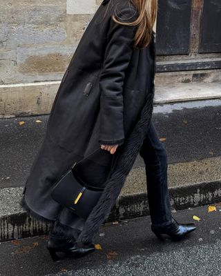 woman wearing long black coat and light black jeans