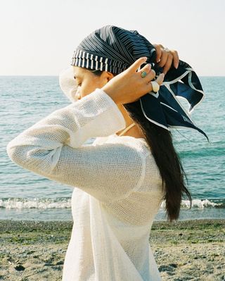 woman wearing printed silk headscarf and white coverup on vacation