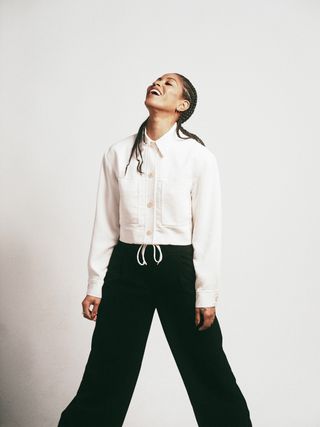 Lex Scott Davis photographed wearing a cropped white button-front jacket with black trousers.