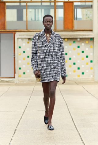 A Chanel model wearing patent-leather moccasins walks the Resort 2025 runway.