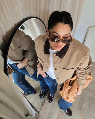 woman wearing barn jacket, jeans, and loafers spring outfit